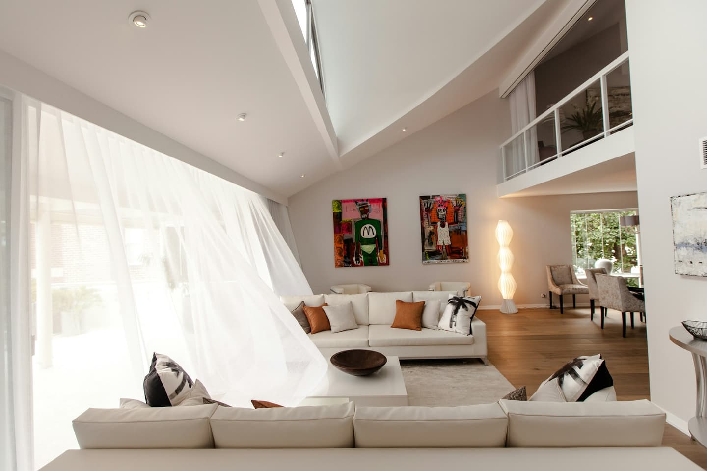 Living amplio y luminoso con cortinas blancas livianas cubriendo un ventanal de piso a techo